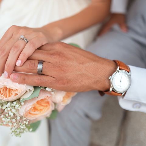 a married couples hands over a bouquet