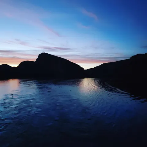 a large body of water with a mountain in the background